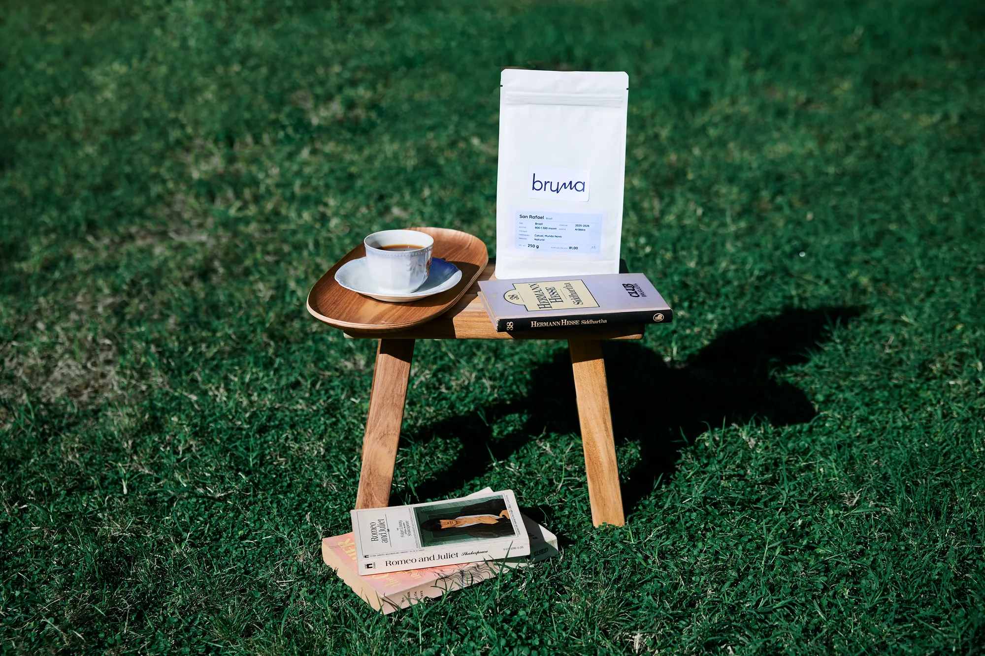 Una bolsa de café Bruma y una taza sobre un taburete en la hierba
